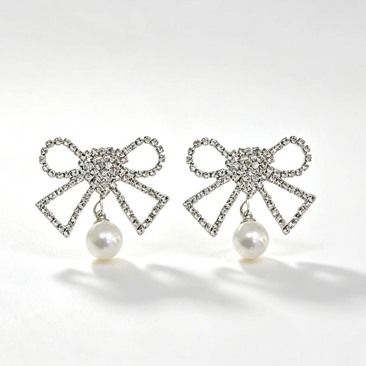 Crystal rhinestone bow earrings with pearl drop pendant in silver tone