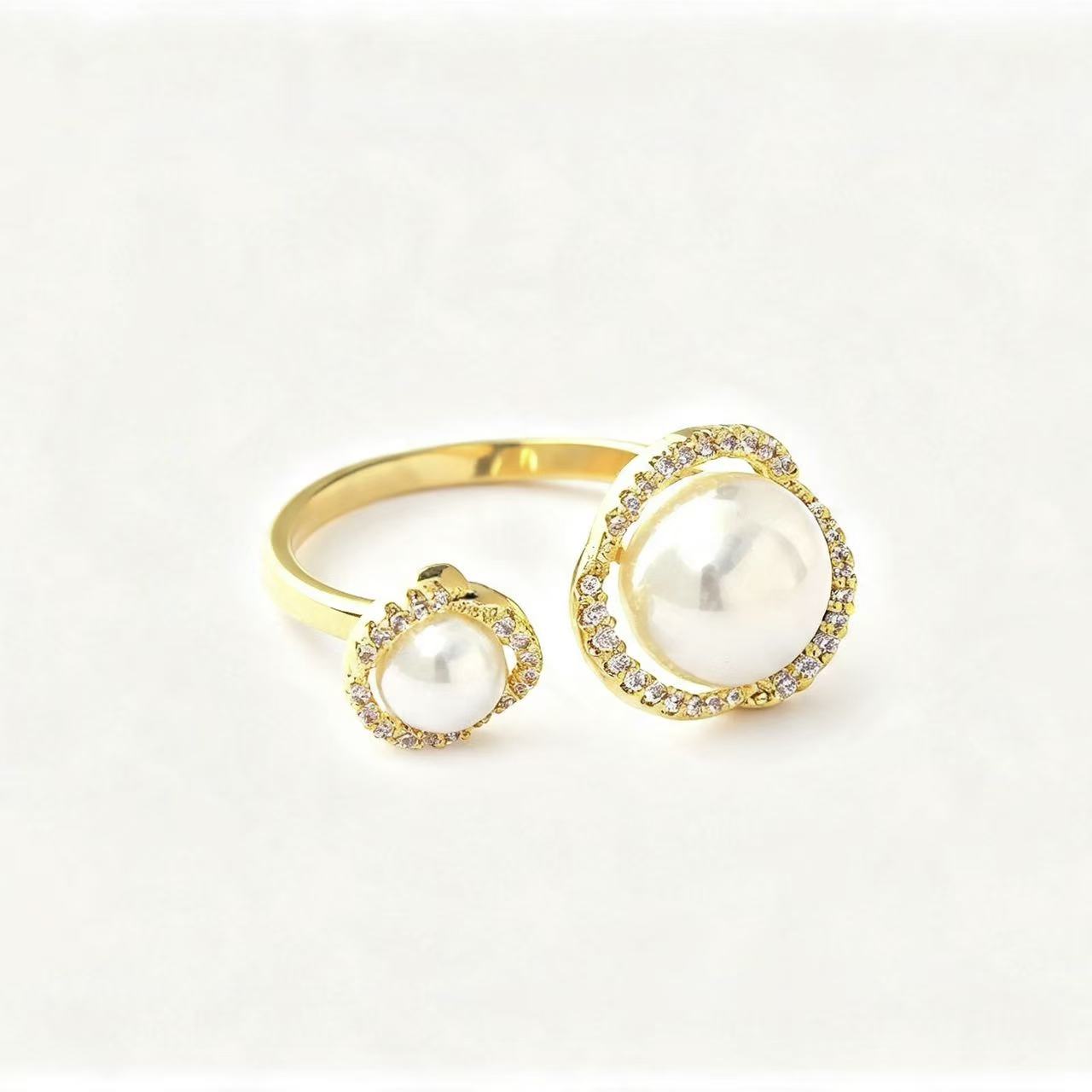 Gold open-band ring with two graduating faux pearls each set in a pavé crystal halo